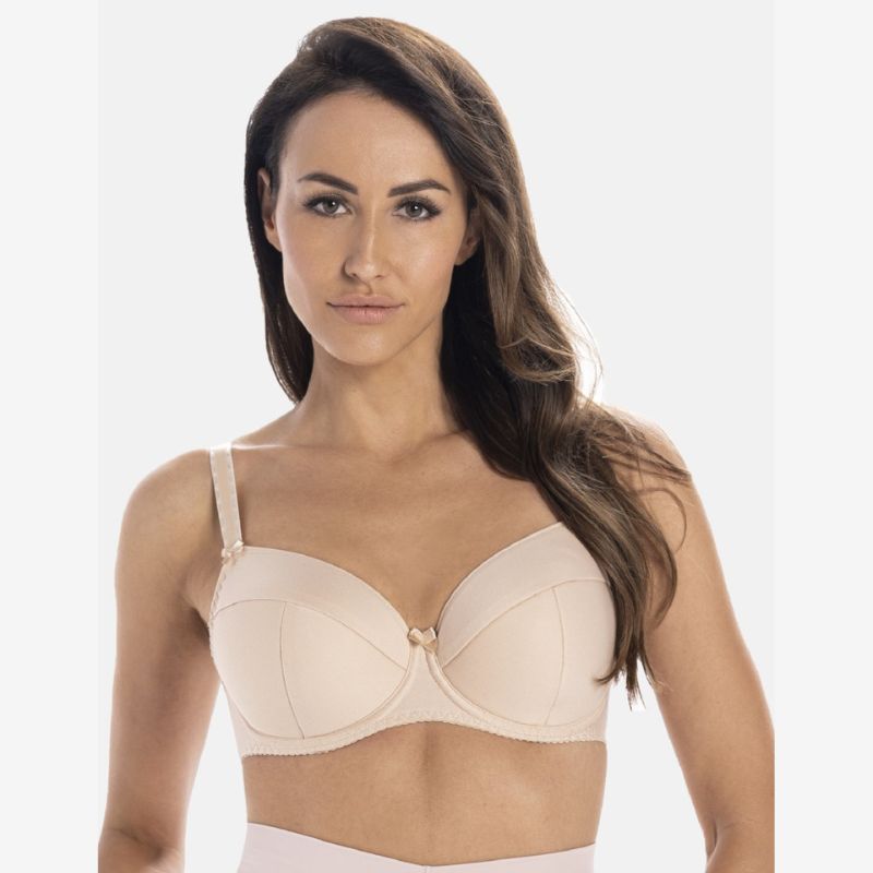 En kvinde med langt brunt hår bærer en Teyli-bh i lys beige med tynde stropper og en lille detalje i midten, mens hun kigger fremad mod en almindelig hvid baggrund med et neutralt udtryk.