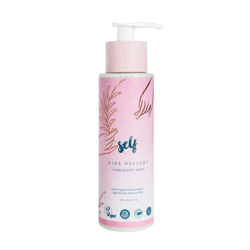 En flaske Natural Self Fine Delight Hand & Body Wash med en pumpedispenser. Den lyserøde etiket har hænder, blade, blå "self"-tekst, produktinformation samt veganske og dermatologisk godkendte ikoner - ideelt til følsom hud og dem, der ønsker en naturlig bodywash.