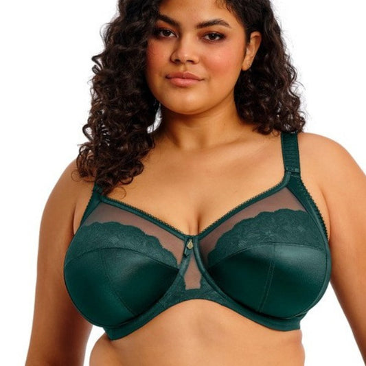 En kvinde med krøllet mørkt hår står model til en Elomi smaragdgrøn bøjle-bh med net- og blondeskåle, der er ideel til kurvede kvinder. Med justerbare stropper og en guldcharm i midten står hun selvsikkert på en almindelig hvid baggrund.
