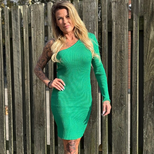 Fest kjole med et ærme. Den ene side er off shoulder og den anden har et langt ærme. Kjolen er grøn med glitter i. Materialet er ribbed.