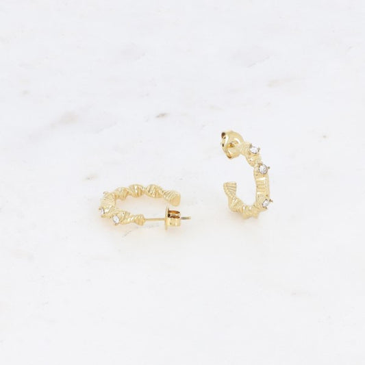 Et par Fashion Paris guld farve øreringe med bølget, struktureret design og små sten vist på hvid marmor - den ene flad for at afsløre stolpen, den anden opretstående for at fremhæve dens elegante kurve.