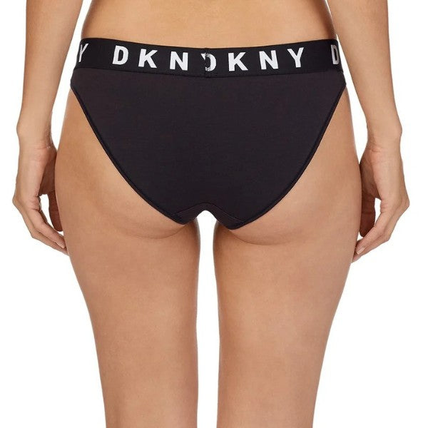 En person vises fra taljen og ned, vendt væk, iført DKNY Cozy Boyfriend truss med en sort linning og markeret hvid DKNY-skrift, der fremhæver den komfortable pasform mod en almindelig, overskuelig baggrund.