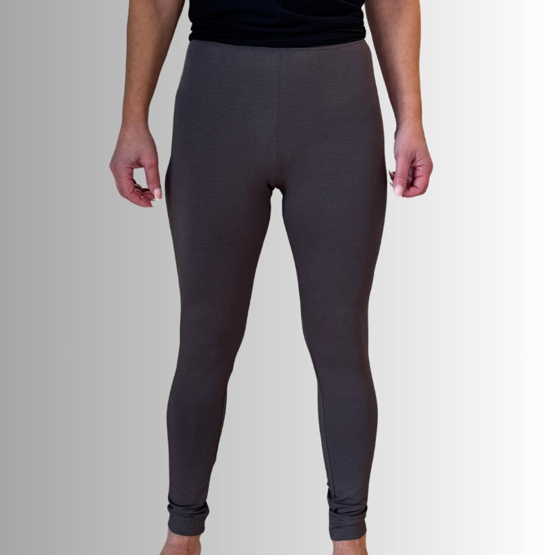 En person står model til E Avantgardes mørkegrå højtaljede leggings med en sort skjorte på en grå til hvid baggrund. Kun underkroppen, benene og hænderne er vist; hoved og fødder er uden for billedet.