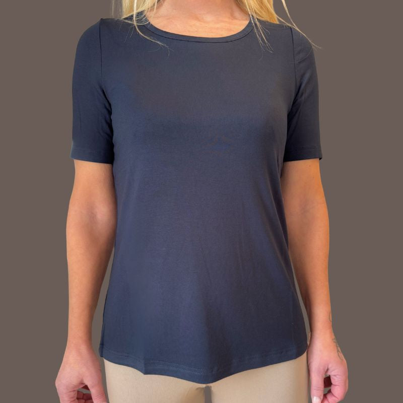 En person i en tætsiddende, kortærmet E Avantgarde mørkegrå T-shirt (OEKO-TEX-certificeret, rund halsudskæring, glat stof) og lysbeige bukser står på en almindelig brun baggrund. Ansigtet er ikke synligt.