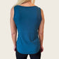 En kvinde med langt blondt hår ses bagfra iført en ærmeløs E Avantgarde OEKO-TEX-certificeret bambus-tanktop og sorte leggings. Den løstsiddende dametop har en lige kant og skiller sig ud fra den ensfarvede, lyse baggrund.