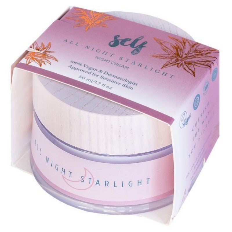 En rund krukke med Natural Self Salt All Night Starlight natcreme med en lyserød etiket er delvist pakket ind i en lilla og lyserød æske dekoreret med stjerner og blade, med mærkets detaljer, dekorativ tekst og "naturlige ingredienser".