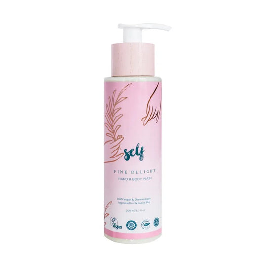 En flaske Natural Self Fine Delight Hand & Body Wash med en pumpedispenser. Den lyserøde etiket har hænder, blade, blå "self"-tekst, produktinformation samt veganske og dermatologisk godkendte ikoner - ideelt til følsom hud og dem, der ønsker en naturlig bodywash.