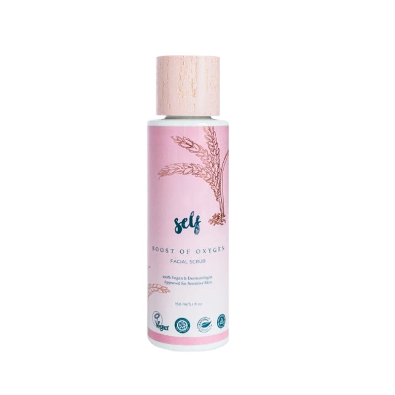 En pink flaske Natural Self Boost of Oxygen Facial Scrub ansigtsscrub med en lys træmønstret hætte. Etiketten viser botaniske illustrationer og fortæller, at den er vegansk, godkendt af dermatologer og lavet med naturlige ingredienser til følsom hud.