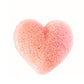 En lyserød, hjerteformet konjac-svamp fra Natural Self sidder centreret på en hvid baggrund. Den er lavet af naturligt konjakpulver og har små huller og en luftig tekstur, som gør den ideel til blid ansigtsrensning.