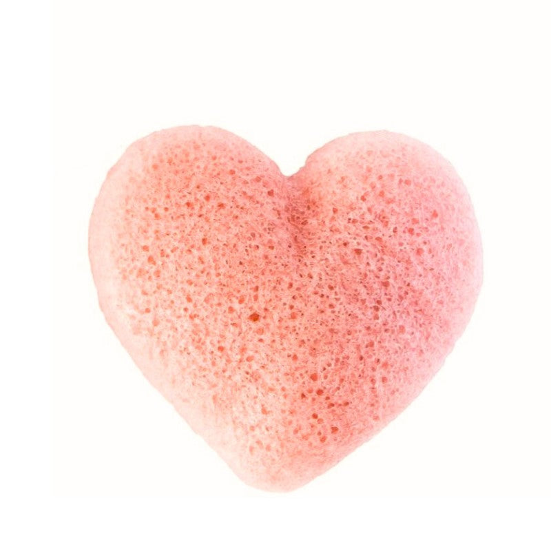 En lyserød, hjerteformet konjac-svamp fra Natural Self sidder centreret på en hvid baggrund. Den er lavet af naturligt konjakpulver og har små huller og en luftig tekstur, som gør den ideel til blid ansigtsrensning.