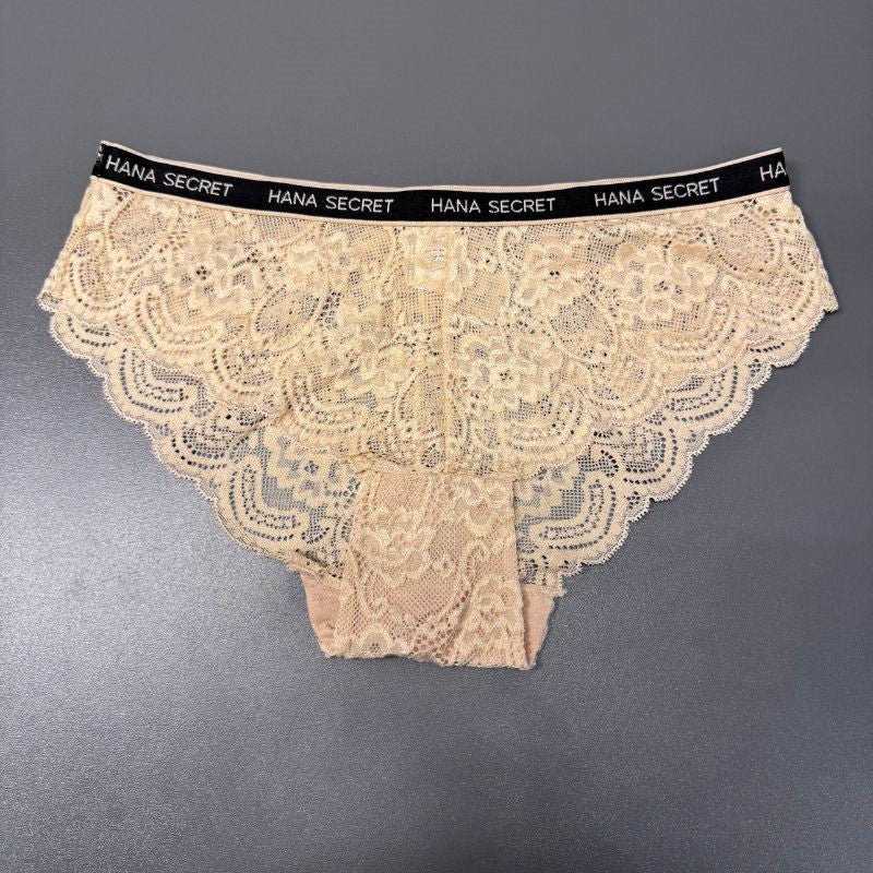 Et par Jessylia lys beige blondetrusser til kvinder med indviklede blomstermønstre og en sort linning trykt med "HANA SECRET" i hvidt, vist fladt på en almindelig grå baggrund.