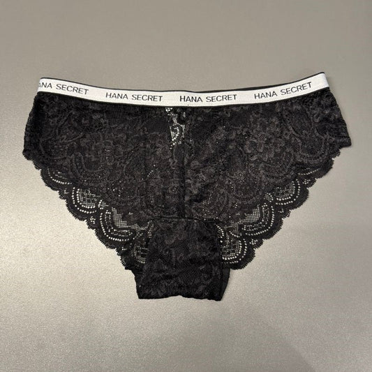 Sort blondetrusse til kvinder fra Jessylia lagt fladt på en grå overflade. Den hvide linning har mærkets navn, mens blomsterblonder og skulpterede kanter giver delikate detaljer.