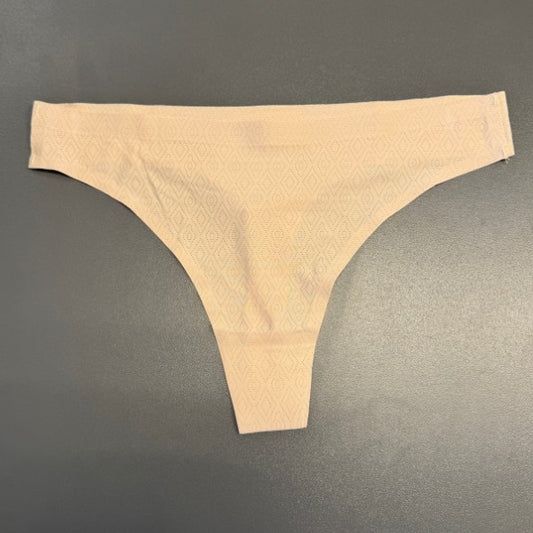 En sømløs lys beige g-streng fra JESSYLIA ligger fladt på en glat grå overflade. Stoffet har et diskret diamantmønster med rene kanter og ingen synlige sømme eller mærker.