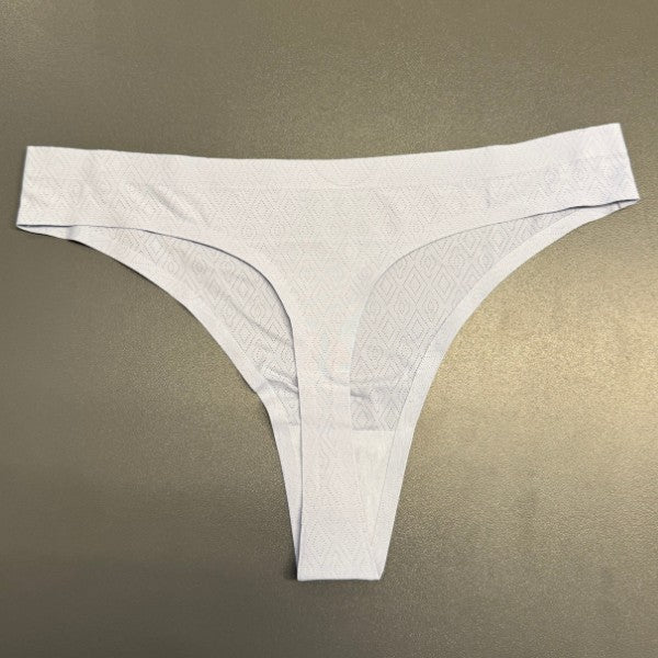 En hvid Jessylia g-streng med et diskret diamantmønster ligger fladt på en glat, beige overflade. Den har blødt, elastisk stof, en bred linning og minimal rygdækning - klassiske elementer i Jessylias g-strengstøj.