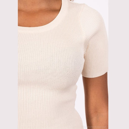 Nærbillede af en person iført MOCHYs kortærmede ribstrik kjole top i lys beige med rund halsudskæring og struktureret stof. Den mellembrune hudtone skaber en elegant kontrast til et stilfuldt MOCHY-look.