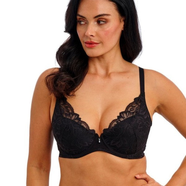 En kvinde med langt mørkt hår og lys hud modellerer en Wacoal Abellia push-up-bh med blomsterblonder, tynde stropper og dyb udskæring. Hun står på en almindelig hvid baggrund og kigger lidt til venstre med et neutralt udtryk.