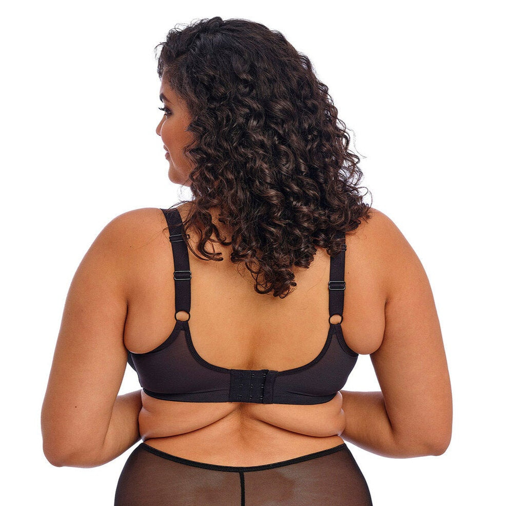 Bagfra, er modellen iført en sort Elomi-bh med justerbare stropper og lukning med flere hægter. 