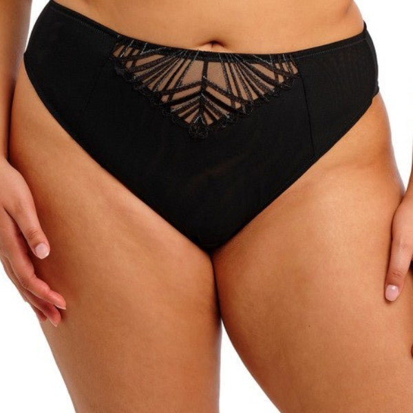 En person bærer Elomi Reja Brazilian brief - en blond trusse med gennemsigtig mesh, geometriske blonder og halvdækkende pasform. Den subtile V-formede accent og den fulde dækning smigrer taljen og hofterne. Mærke: Elomi.