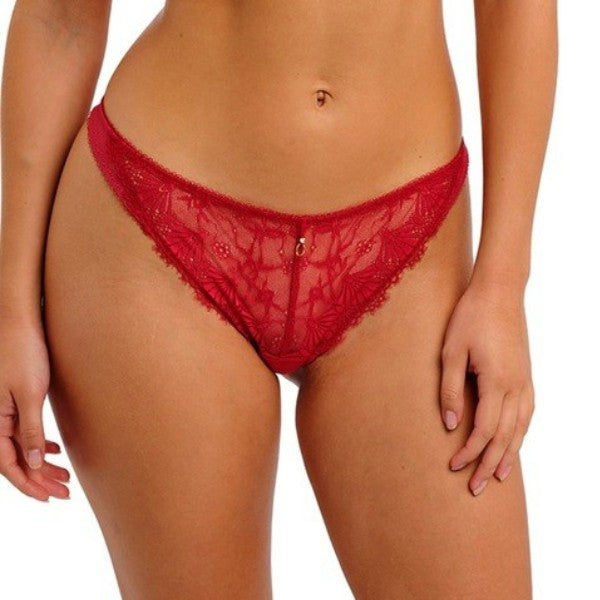 En kvinde står model til Freya rød blonde trusse med en lille charm foran. Trusserne har et blomstret hulmønster og skulpterede kanter, som fremhæver elegante og feminine lingeri på en ensfarvet baggrund.