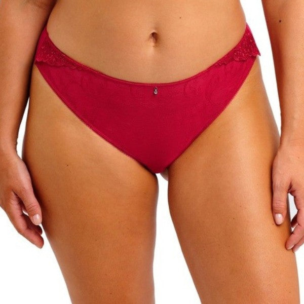 En person modellerer Fantasie Portia Brazilian trusse-rød, med fine broderidetaljer og en lille charm i midten af linningen, vist fra midt på torsoen til øvre lår mod en almindelig hvid baggrund.
