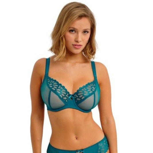 En kvinde med skulderlangt blondt hår bærer Freya Bombshell Teal plunge-bh'en med gennemsigtige paneler og dekorative blonder langs de øverste kanter. Hun står med ansigtet fremad mod en almindelig hvid baggrund.